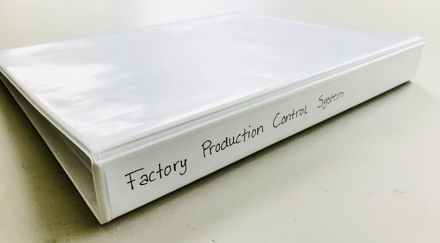 Billede af mappe med teksten "Factory Production Control System" skrevet bagpå.